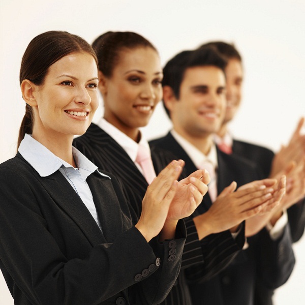 Close-up of four business executives standing in a line and applauding